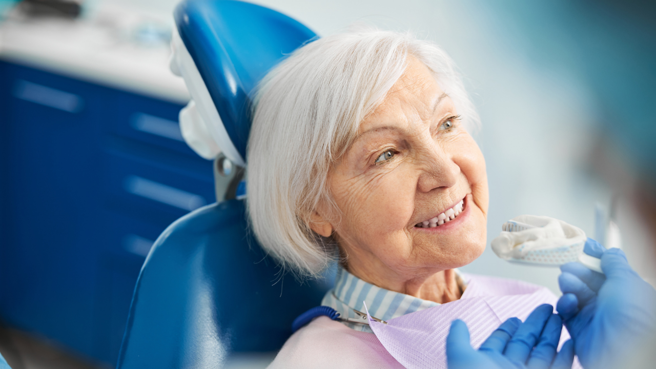 Older lady sitting in a dentist chair smiling with dental impression tray near her mouth
