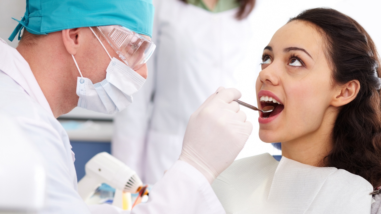 Dentist looking inside a patient's mouth with a dental tool